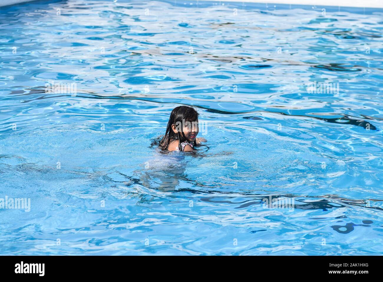 Pretty girl smiling et nager dans la piscine extérieure Banque D'Images