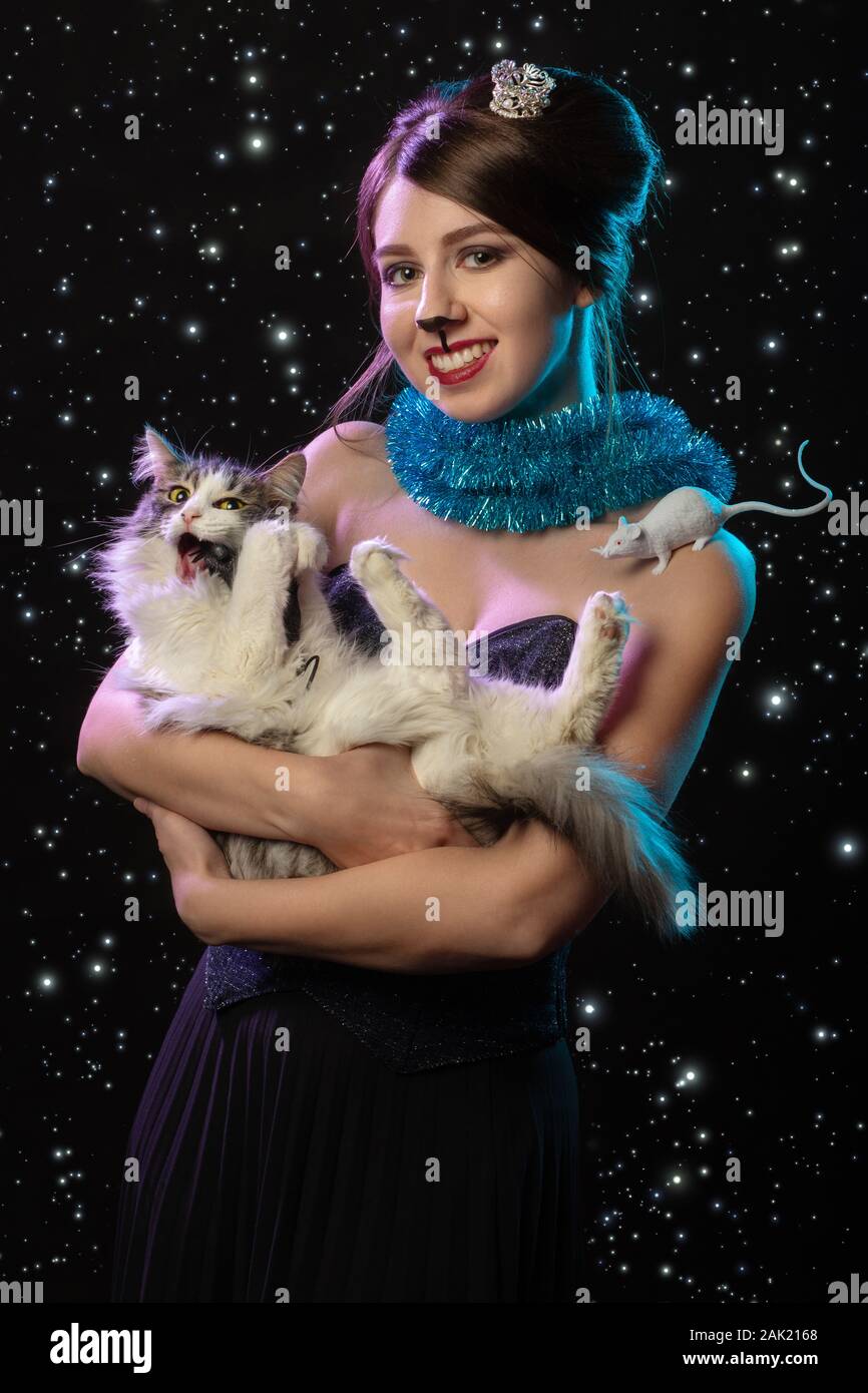 Happy girl avec la souris maquillage Queen hugs cat sur stars de fond looking at camera, smiling Banque D'Images
