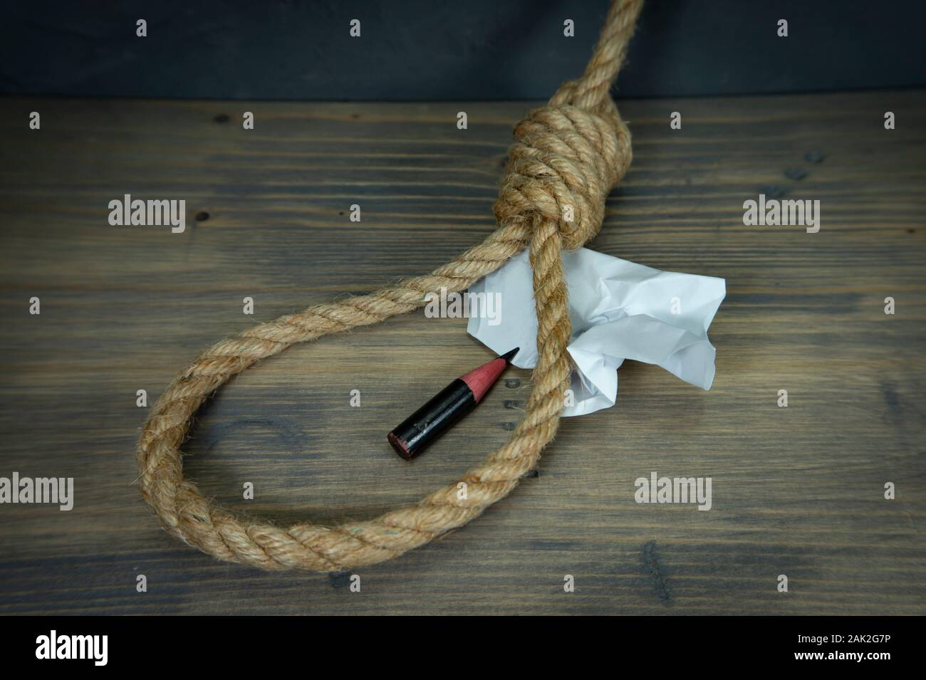 Corde corde autour de papier froissé et un court tronçon de crayon sur une table en bois rustique dans une image conceptuelle Banque D'Images