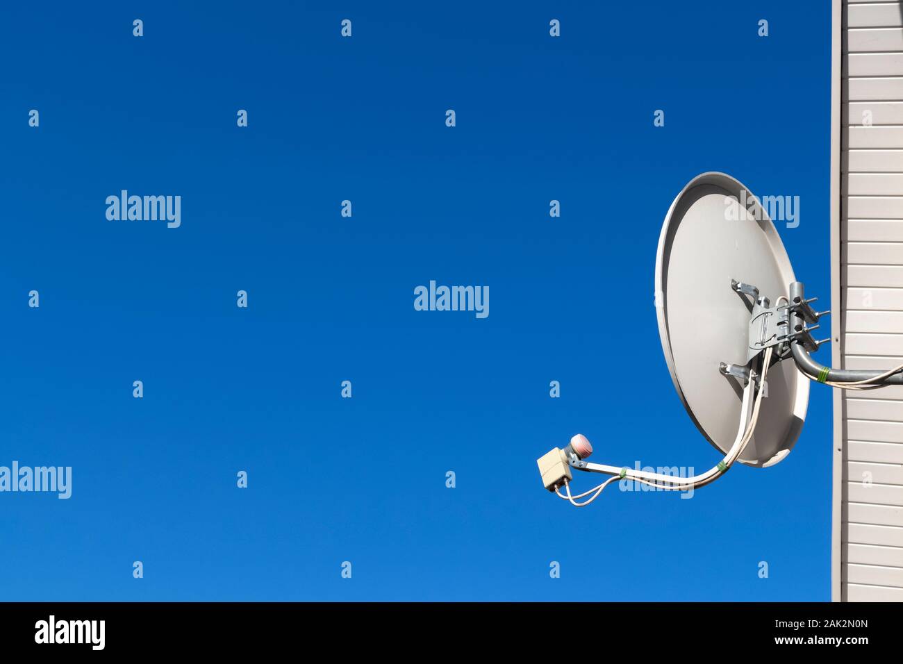 Télévision par satellite plat sur le mur de la maison contre le ciel bleu. Banque D'Images