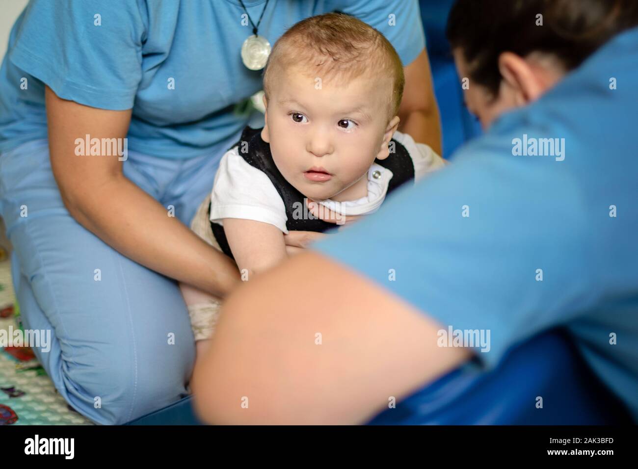 Portrait d'un bébé souffrant de paralysie cérébrale sur la physiothérapie au centre de thérapie pour enfants. Garçon avec handicap a la thérapie en faisant des exercices. Besoins spéciaux. Banque D'Images