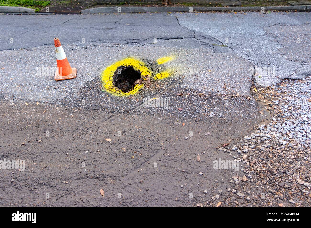 Pot trou dans la chaussée routière américaine avec la peinture jaune d'avertissement et traffic cone Banque D'Images
