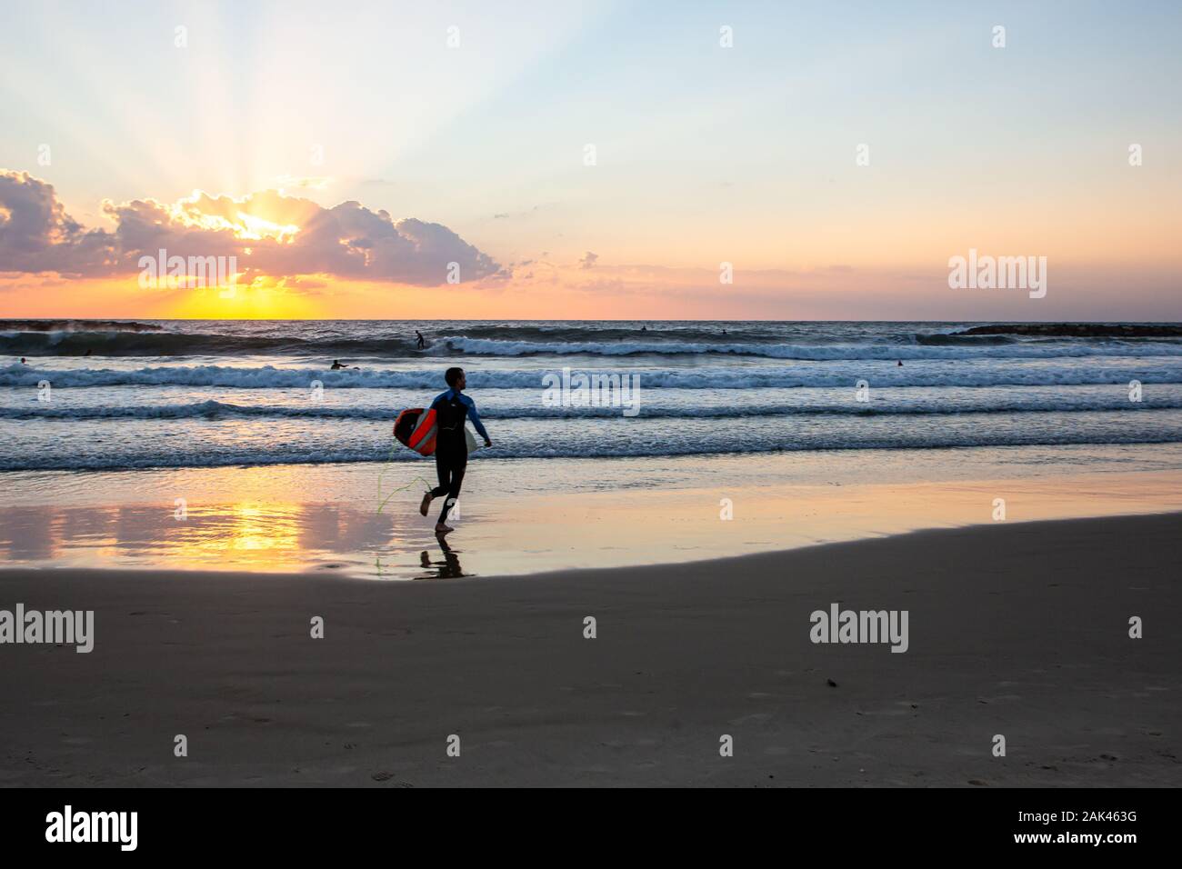 Silhouette de surfers sur la plage de la mer Méditerranée. Photographié à Tel Aviv au coucher du soleil Banque D'Images