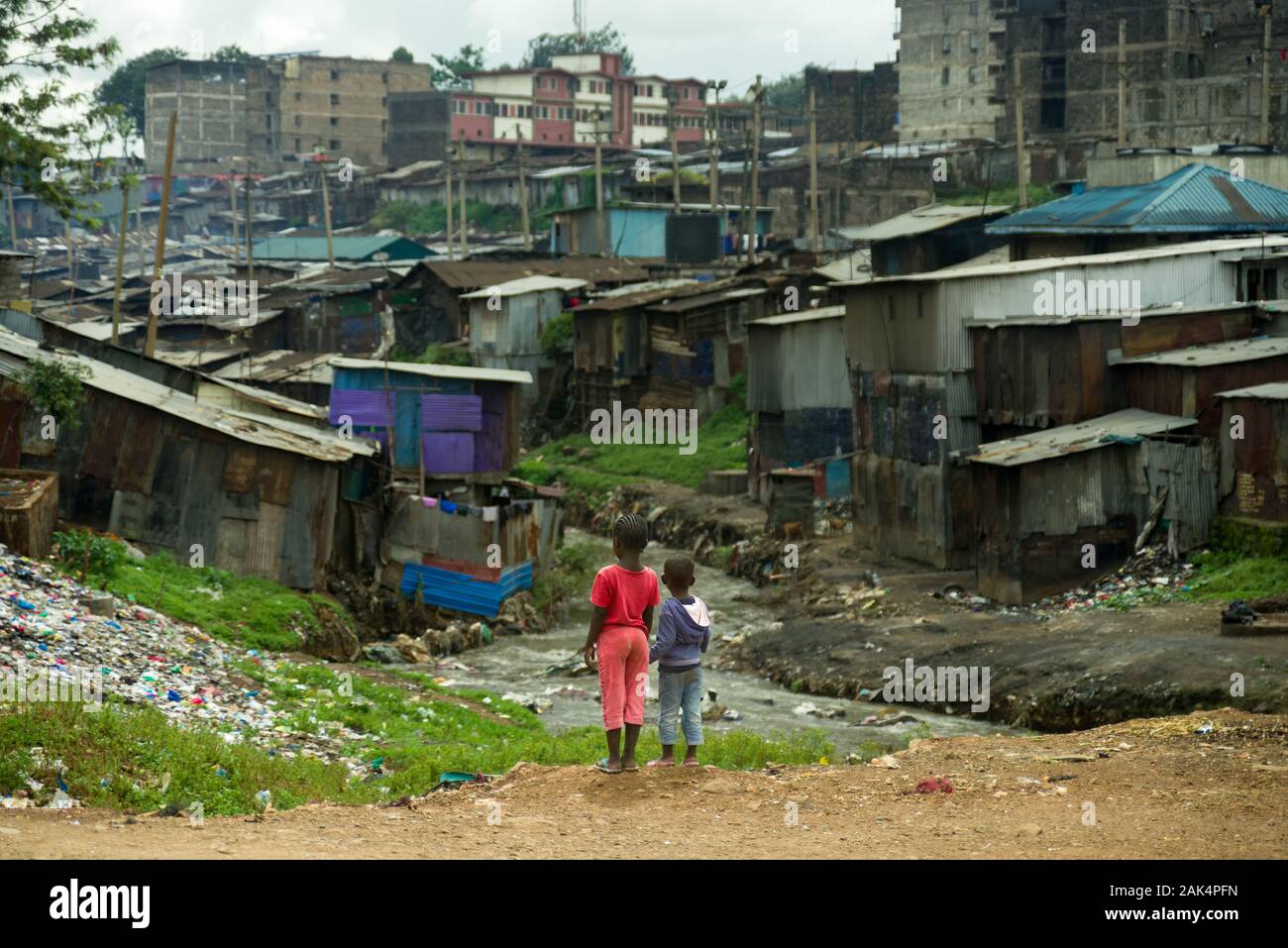 Deux jeunes enfants kenyans se tenir à l'égard de la rivière et dans les bidonvilles de Mathare, à Nairobi, Kenya Banque D'Images