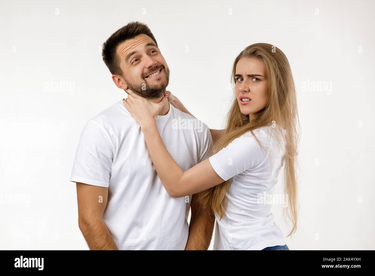 Femme Homme étrangle en plaisantant. femme en colère en criant à son petit ami heureux sur fond blanc. Banque D'Images