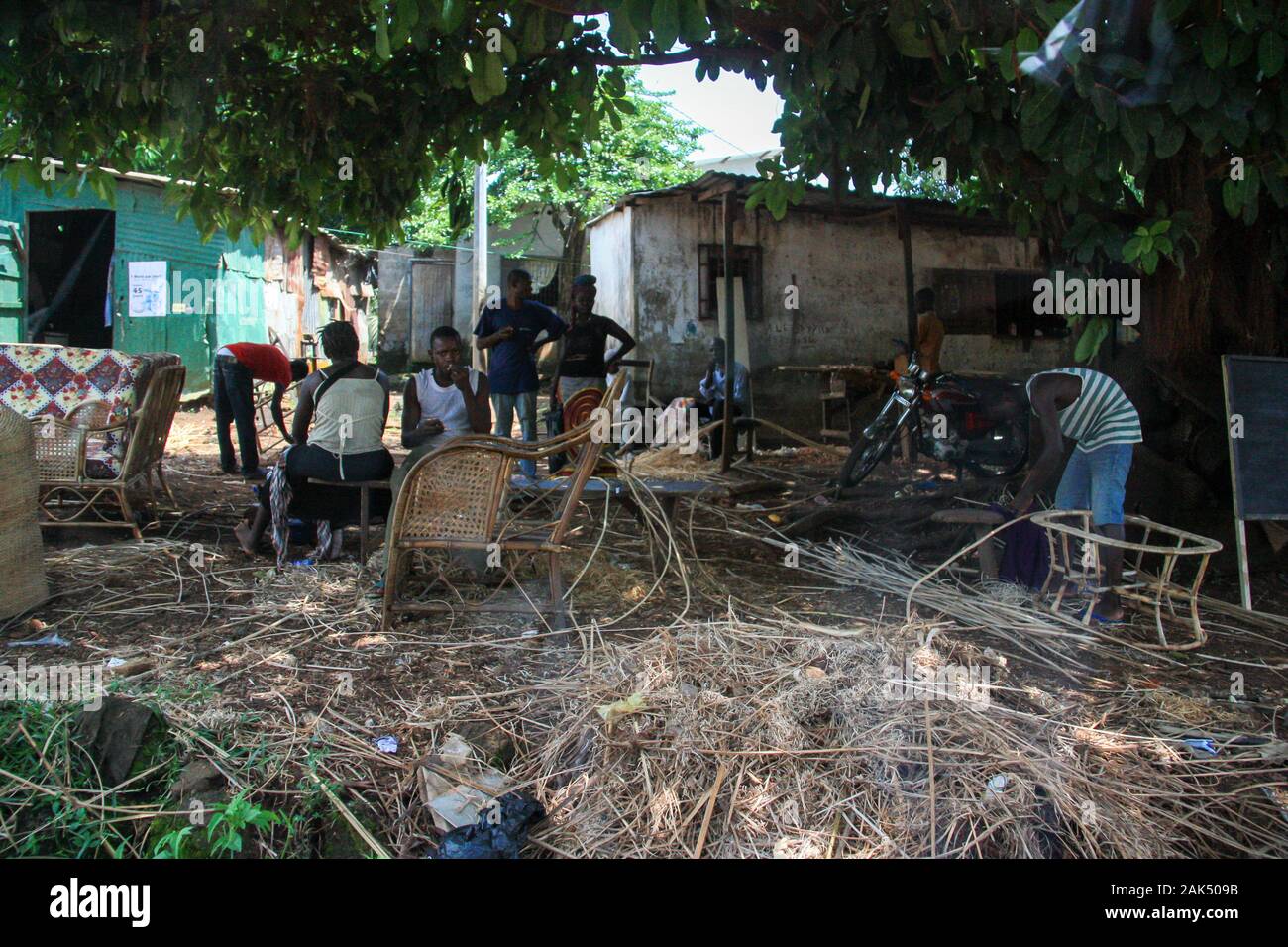 Des chaises en osier tressée pour hommes sur un site de production à côté d'un simple magasin de meubles de plein air à Conakry, Guinée, Afrique de l'Ouest Banque D'Images
