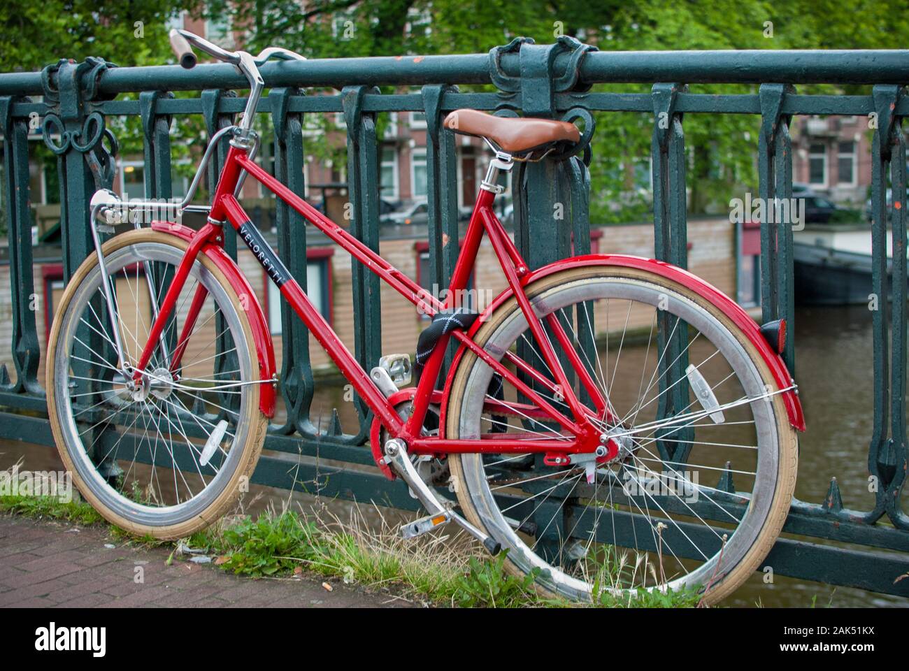 Vélo rouge stationné sur le pont avec un verrou de chaîne Banque D'Images