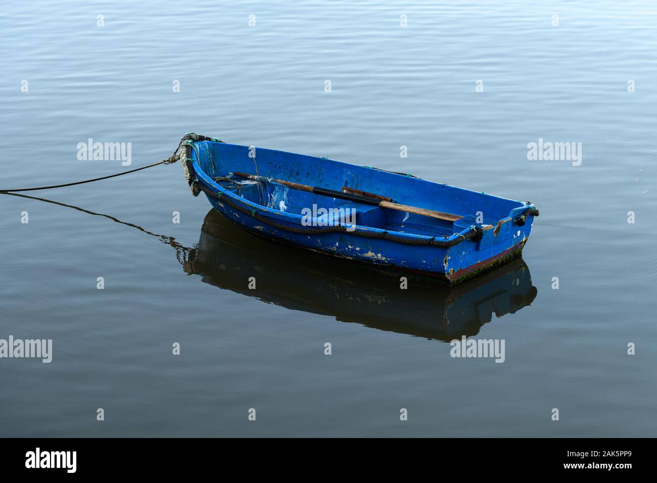 Bateau à rames bleu reflété sur l'eau calme Banque D'Images