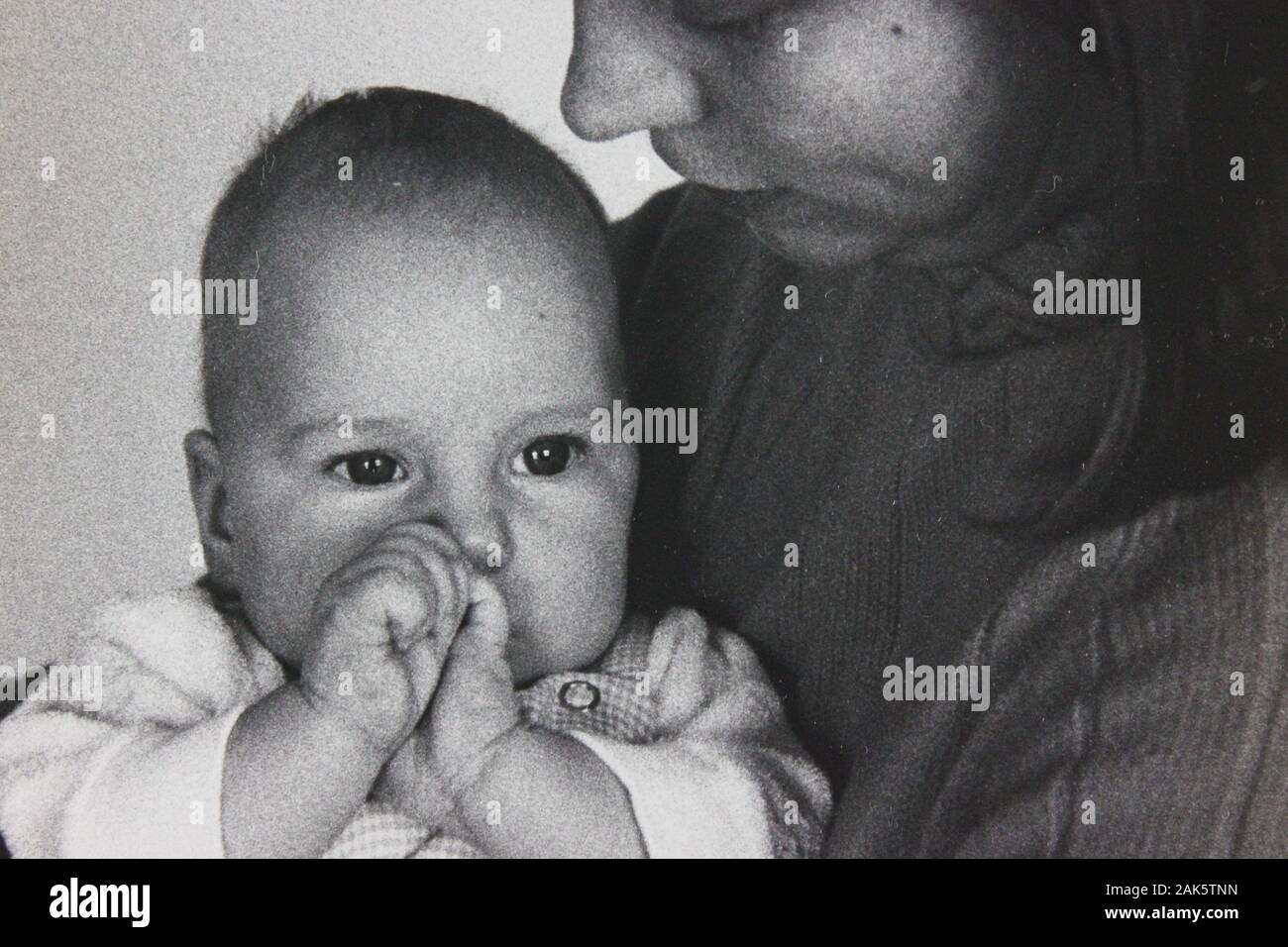 Belle photographie vintage noir et blanc des années 1970 d'un bébé assis sur les genoux de sa mère Banque D'Images
