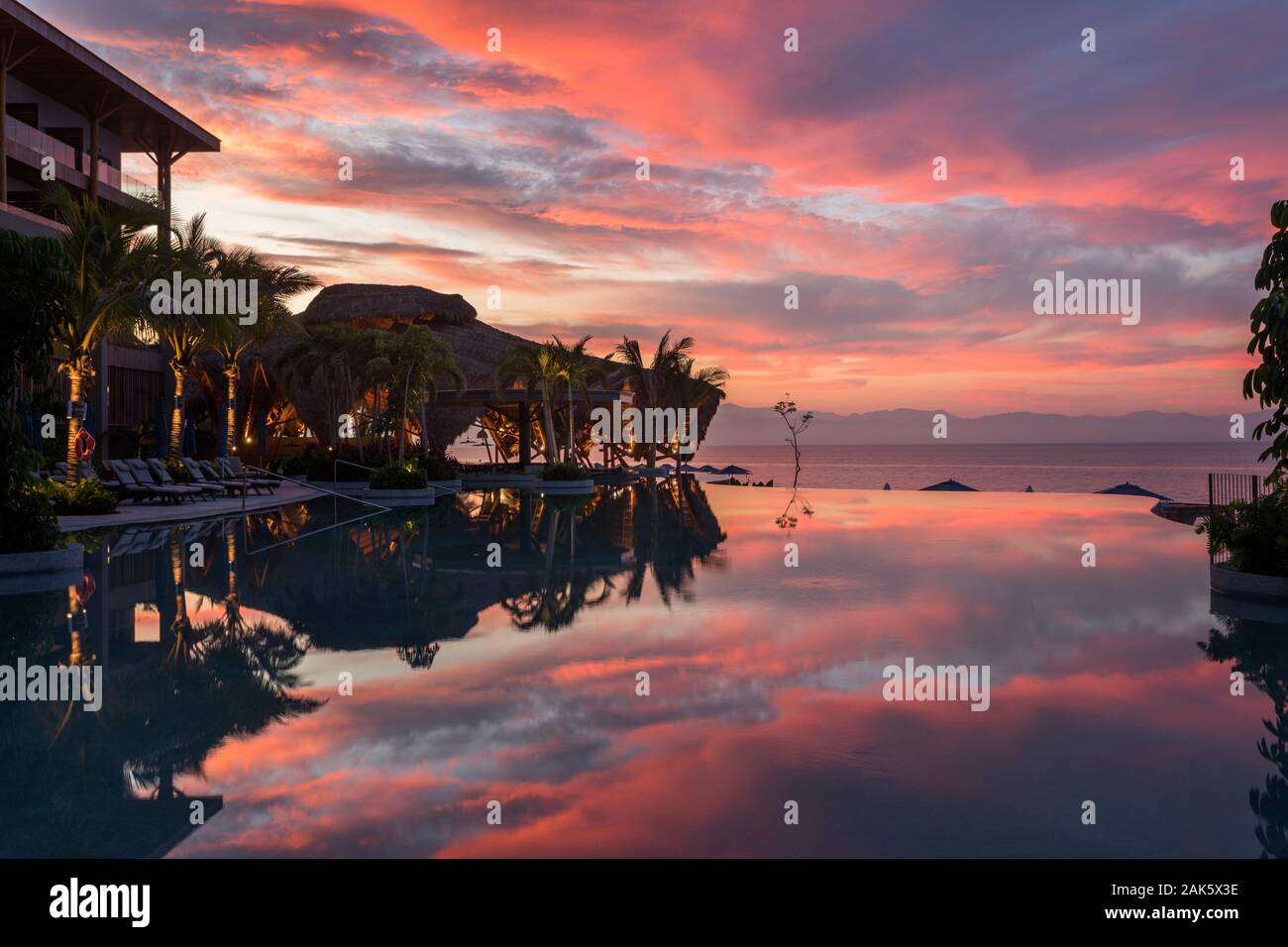 Le Mexique, Nuevo Vallarta, Nayarit,nuages colorés lever du soleil reflétée dans une piscine à Marival Resort Armony Banque D'Images