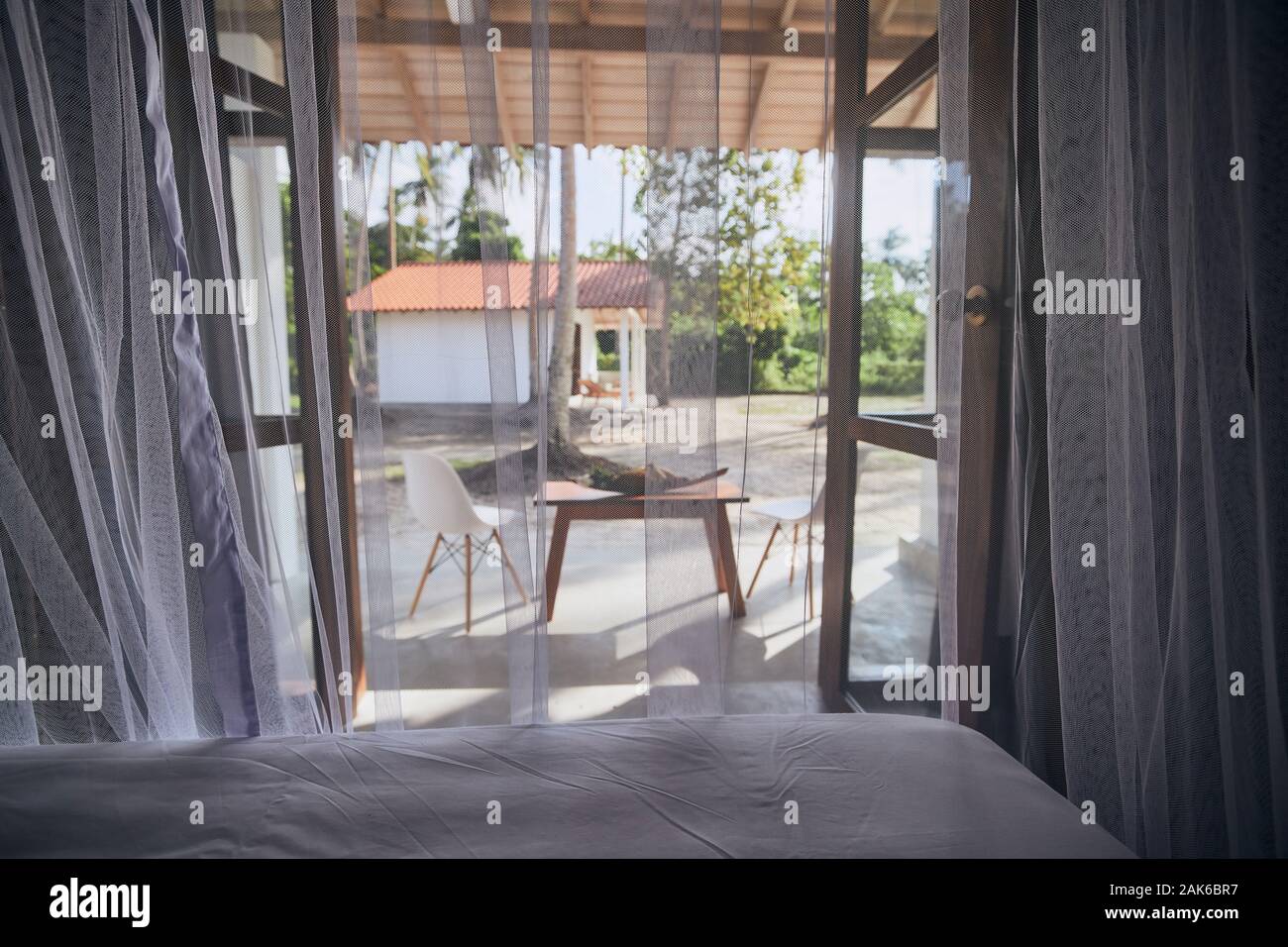 Hébergement de luxe à destination tropicale. Selective focus on moustiquaire dans la chambre du bungalow avec vue sur jardin. Banque D'Images