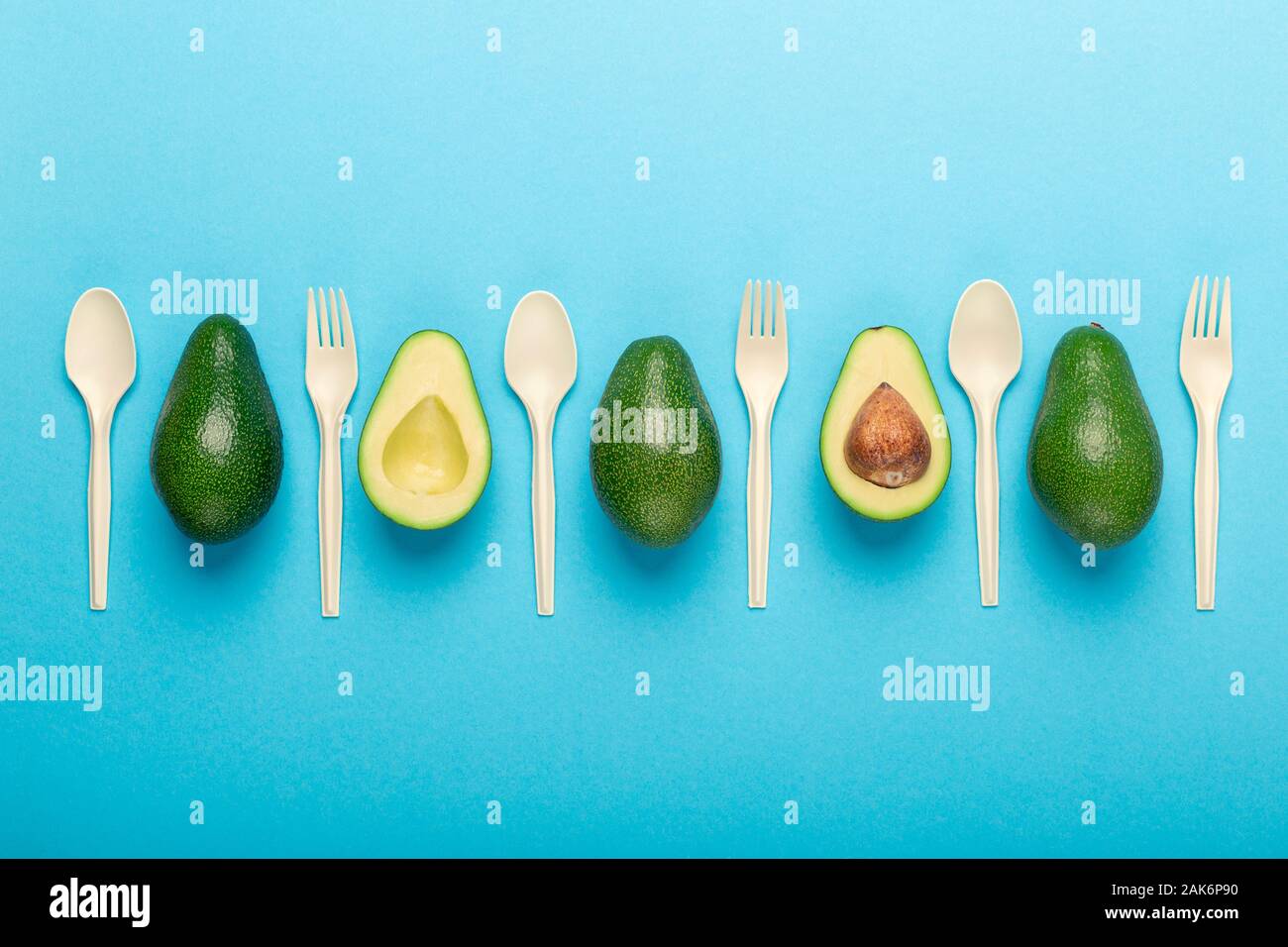 Plastique de rechange, sauver l'environnement. Fourchette et cuillère de graines d'avocat sur fond bleu Banque D'Images
