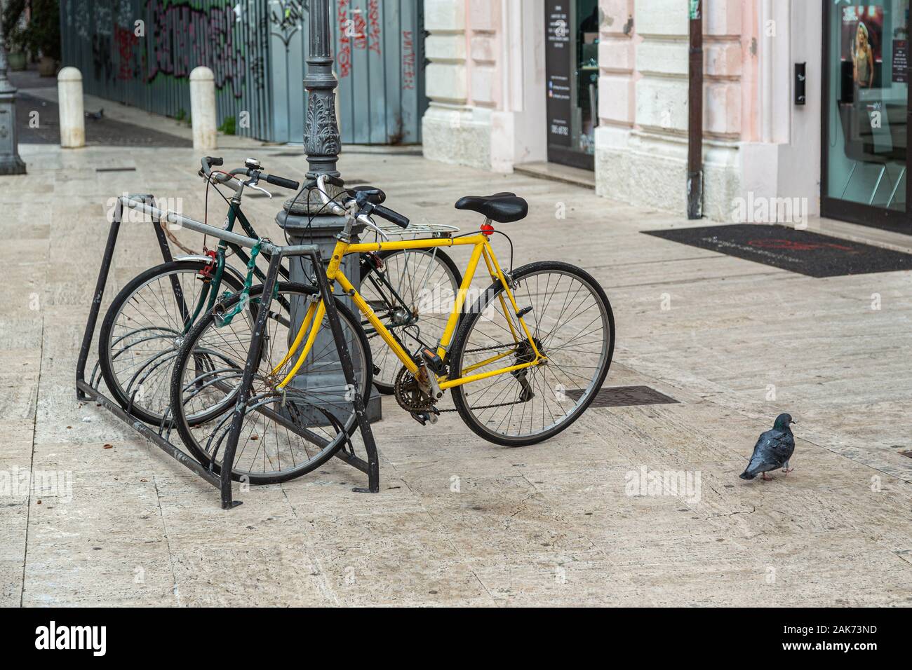 paire de bicyclettes, noires et jaunes enchaînées au lampadaire et au pigeon. Pescara, Abruzzes, Italie, Europe Banque D'Images
