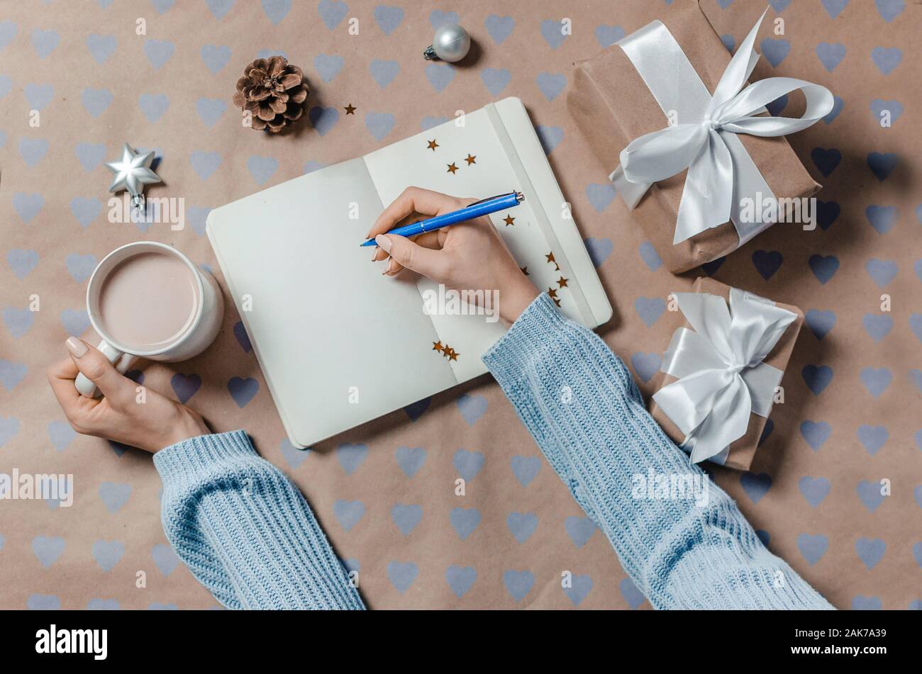 L'écriture féminine dans la liste de souhaits de cadeaux près de l'ordinateur portable Banque D'Images