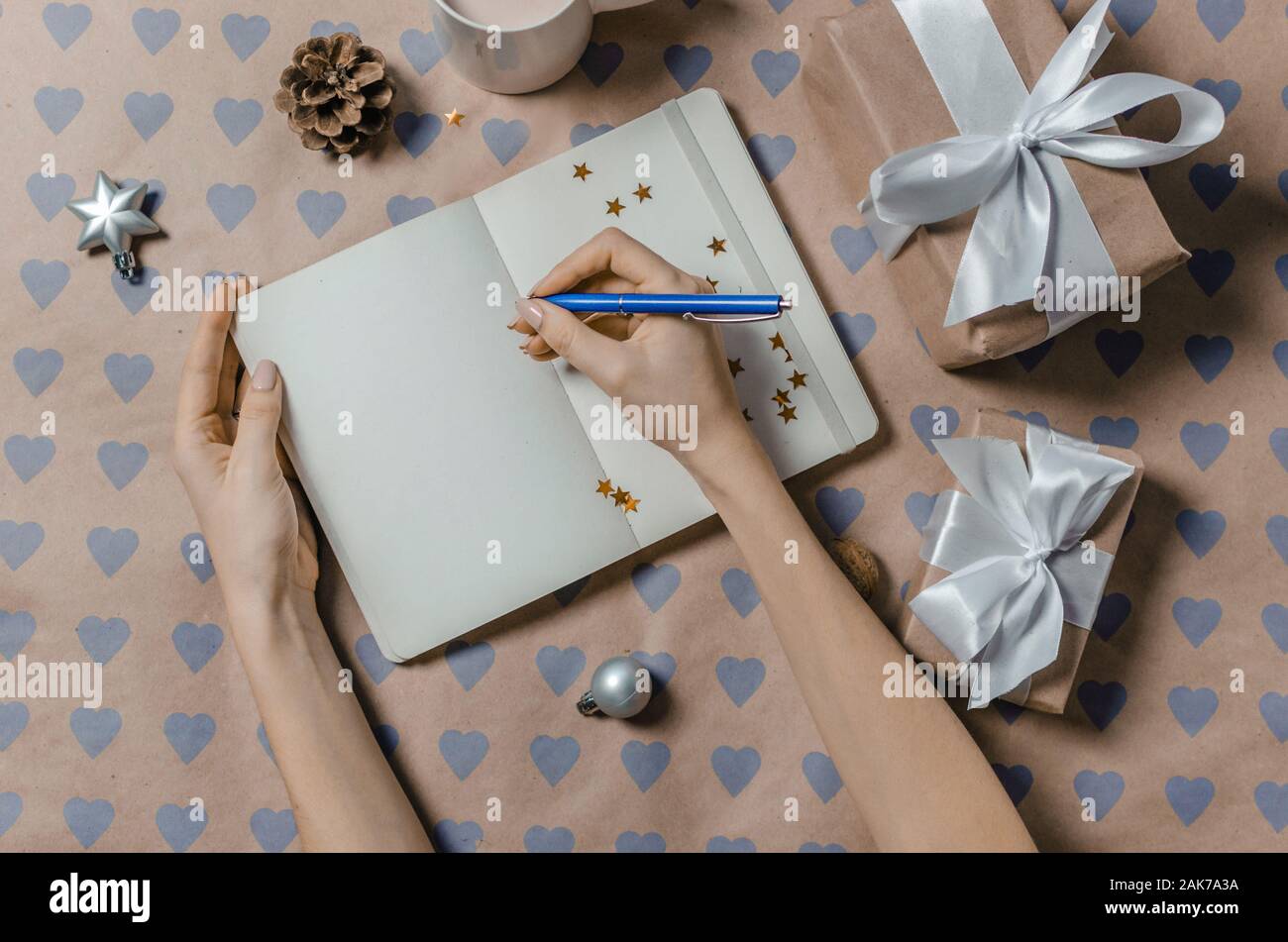 L'écriture féminine dans la liste de souhaits de cadeaux près de l'ordinateur portable Banque D'Images