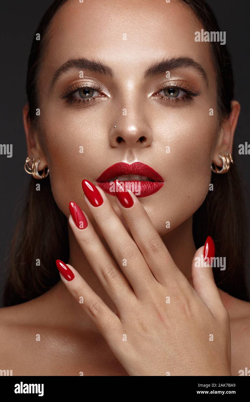 Belle fille avec un classique le maquillage et les ongles rouges. Conception de manucure. Beauté Visage. Banque D'Images