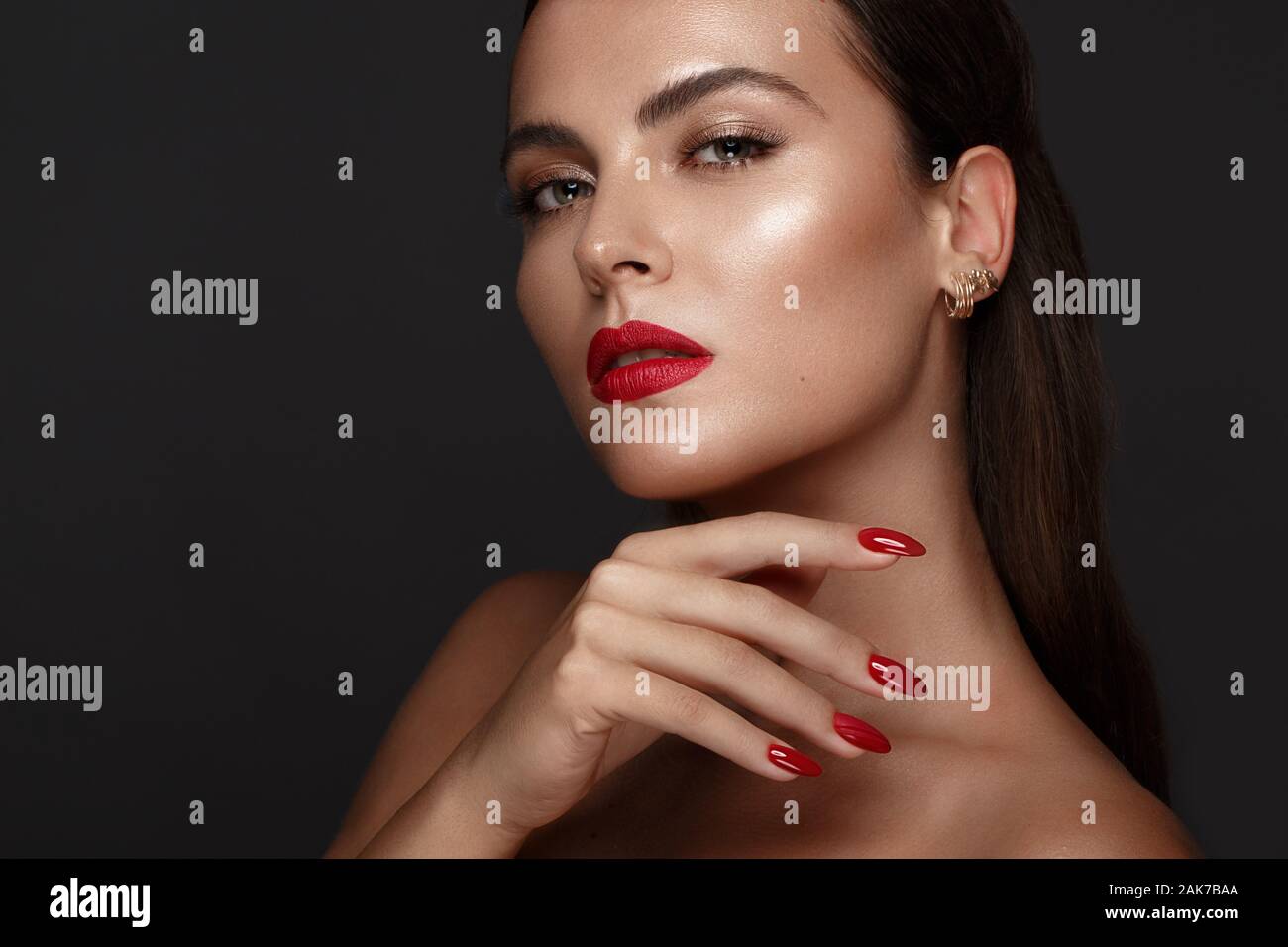 Belle fille avec un classique le maquillage et les ongles rouges. Conception de manucure. Beauté Visage. Banque D'Images