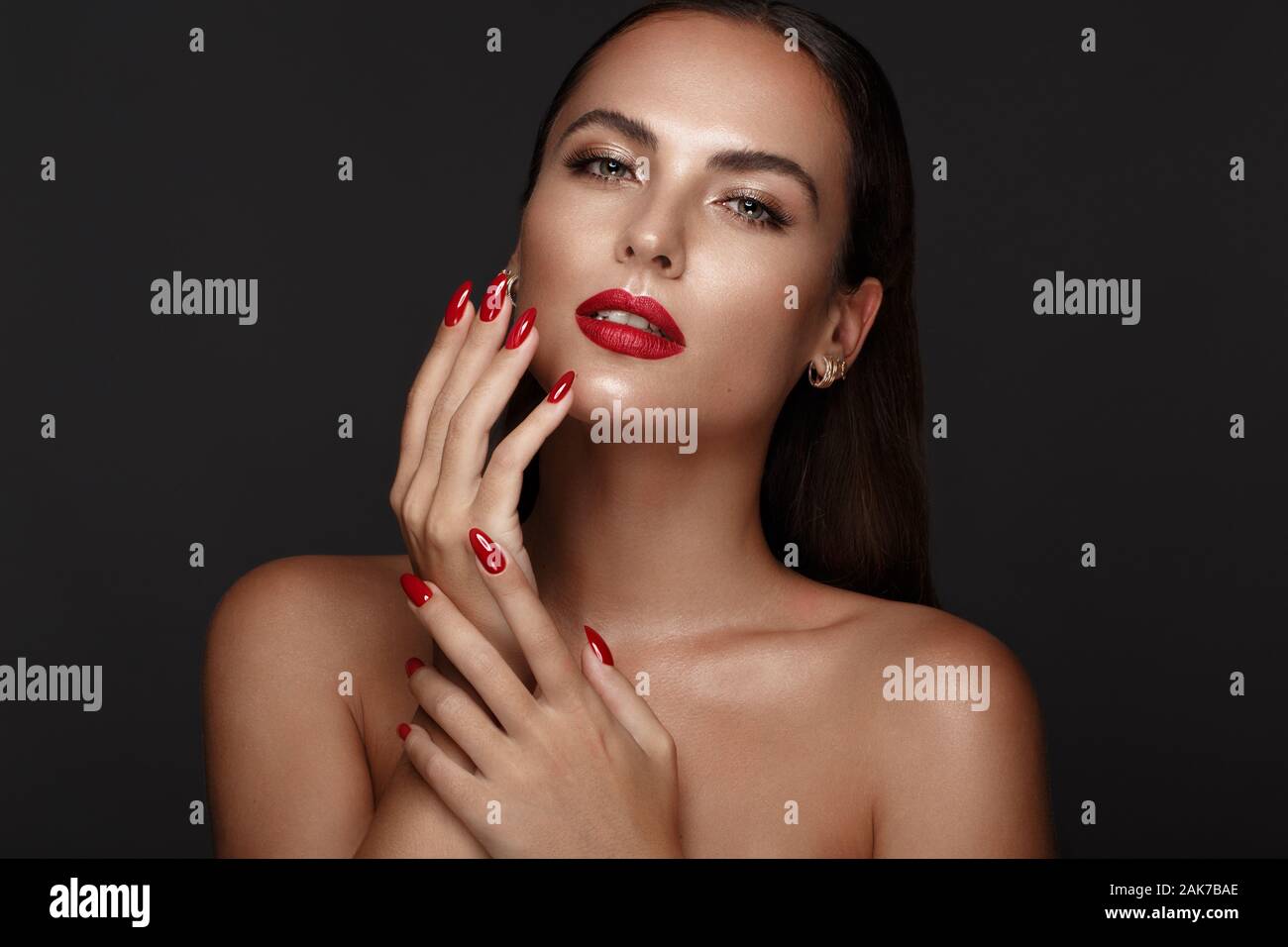 Belle fille avec un classique le maquillage et les ongles rouges. Conception de manucure. Beauté Visage. Banque D'Images