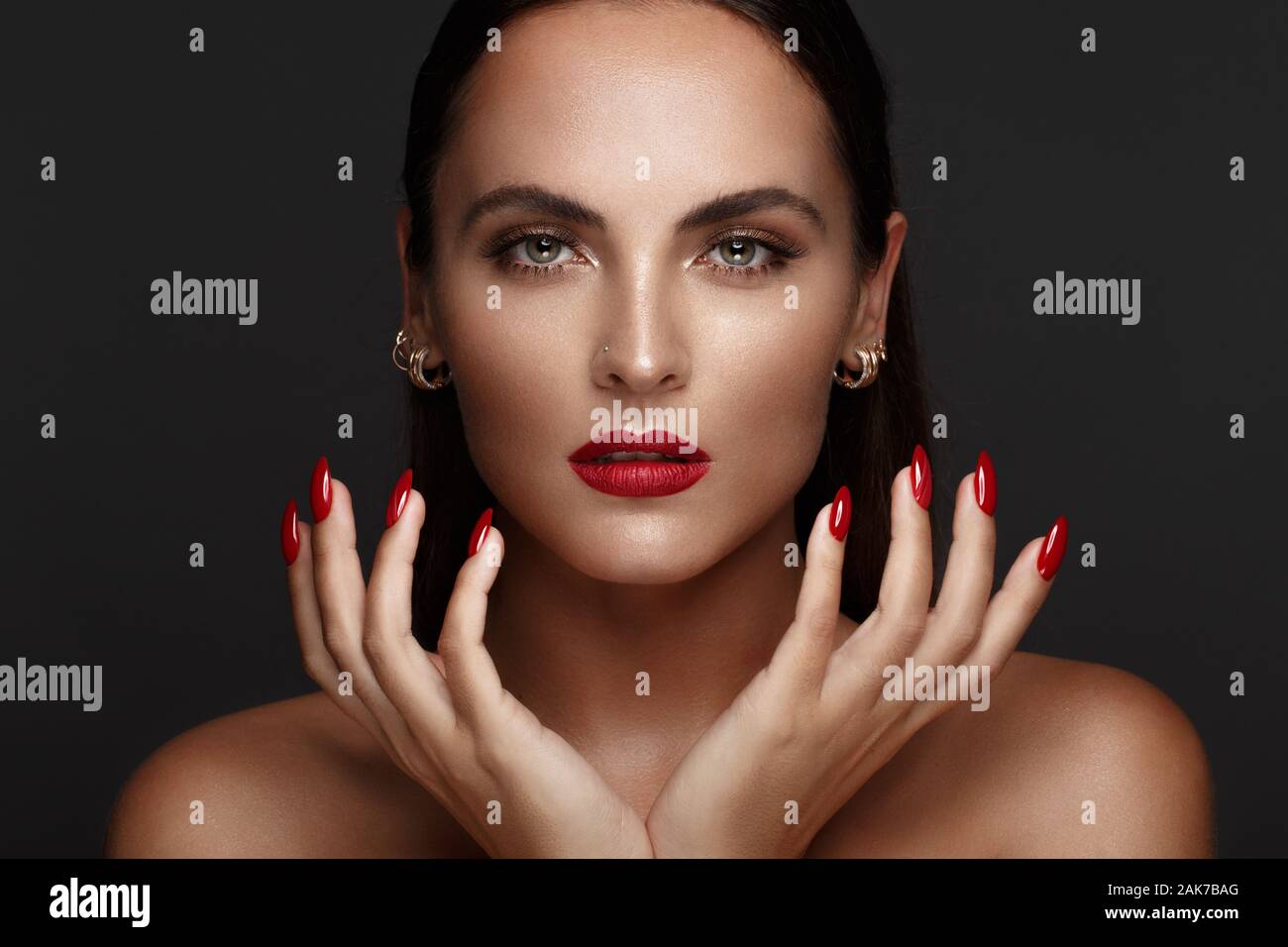 Belle fille avec un classique le maquillage et les ongles rouges. Conception de manucure. Beauté Visage. Banque D'Images