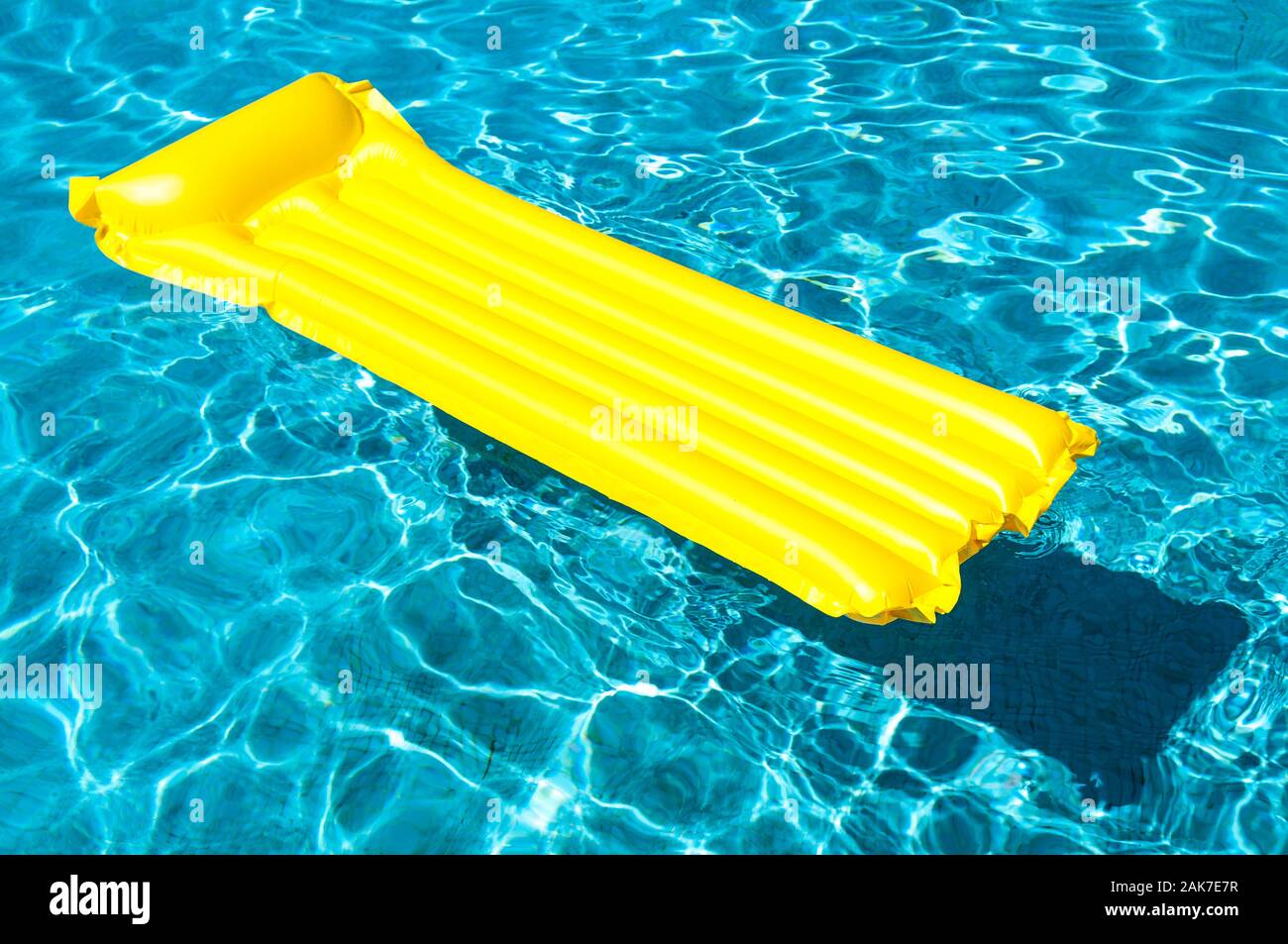 En radeau pneumatique vide flottant lumineux sur bleu piscine en plein soleil Banque D'Images