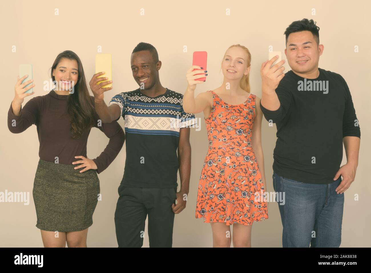 Studio shot of happy groupe diversifié de multi ethnic friends smiling tout en prenant des photos avec des téléphones portables selfies ensemble Banque D'Images