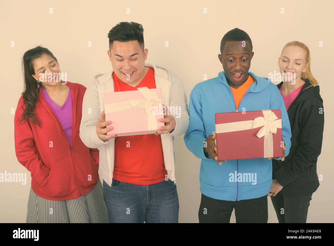 Studio shot of happy groupe diversifié de multi ethnic friends smiling lors de l'ouverture des boîtes-cadeaux et à choqué ensemble Banque D'Images