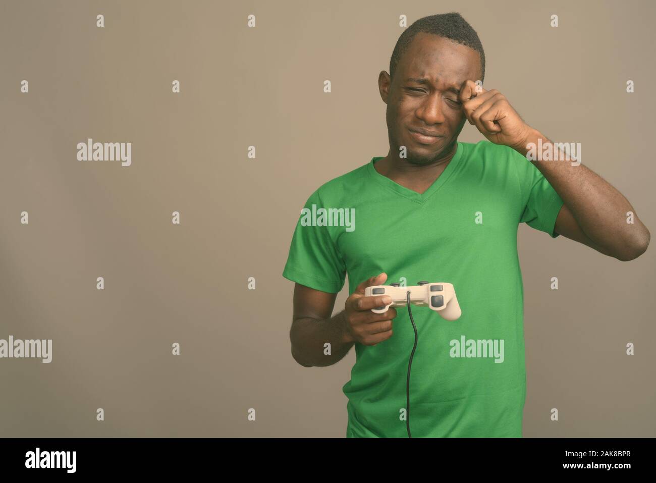 Young African man wearing green shirt contre l'arrière-plan gris Banque D'Images