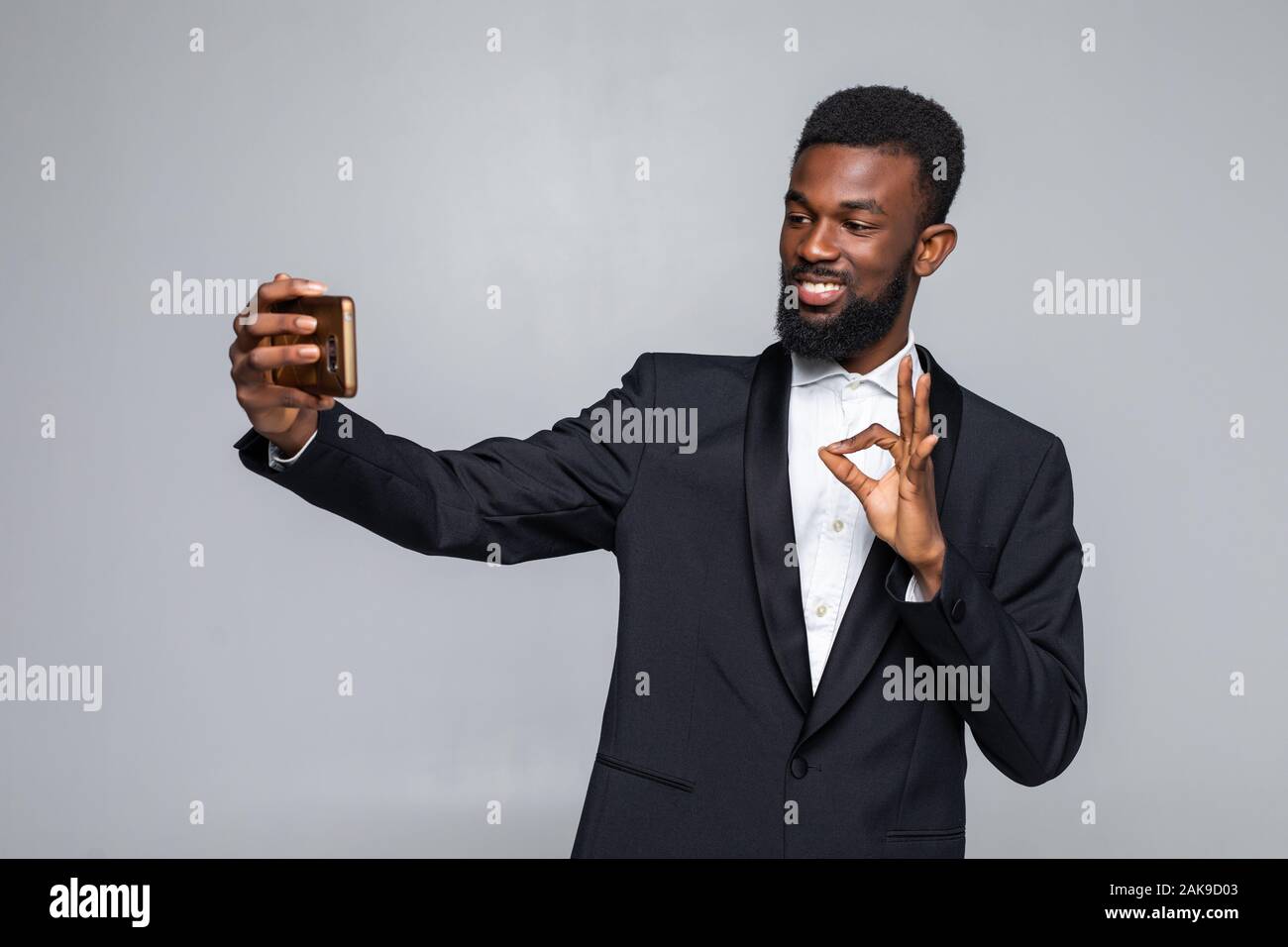 Young African man in suit en tenant avec selfies bon geste isolé sur fond gris Banque D'Images
