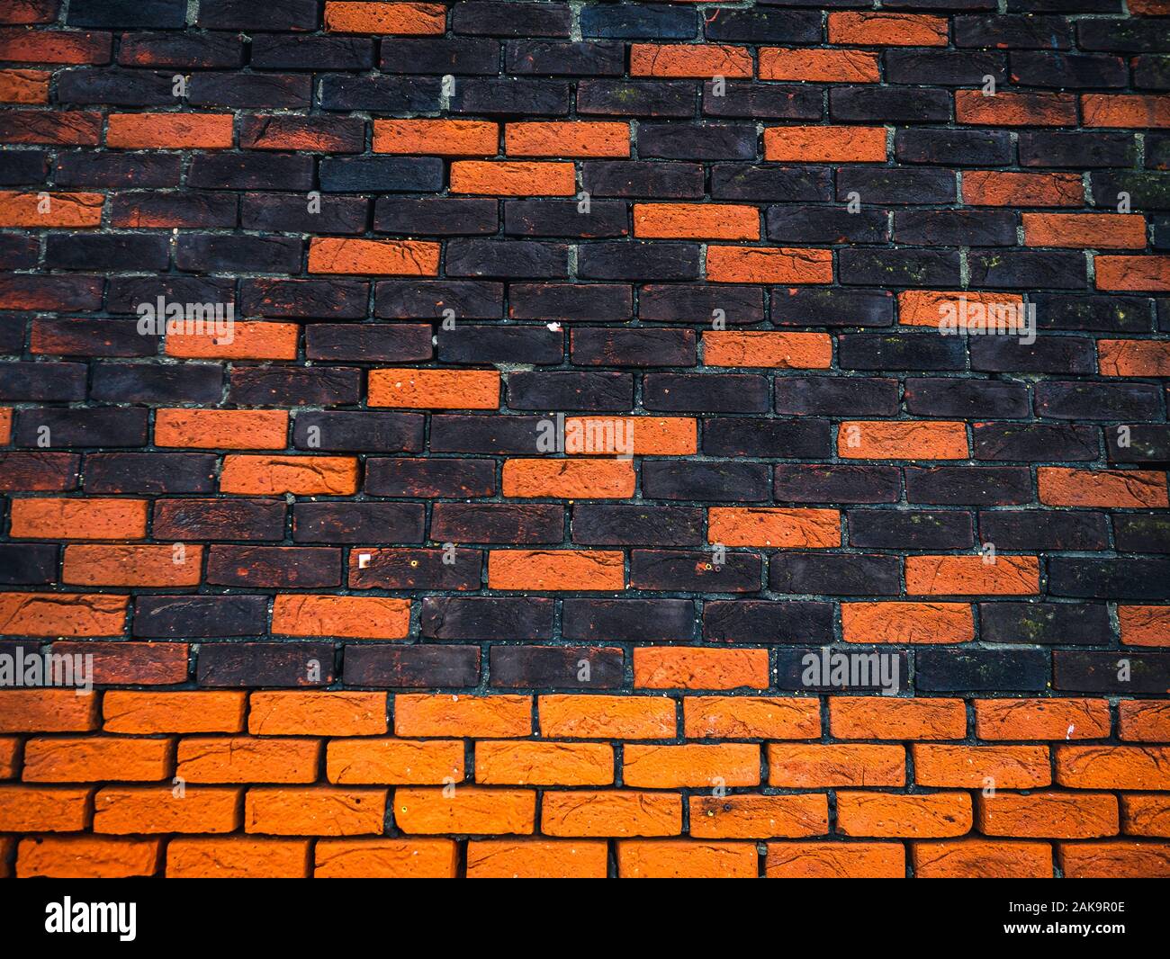 Mur en briques orange et noir avec Textures et tons multiples. Banque D'Images