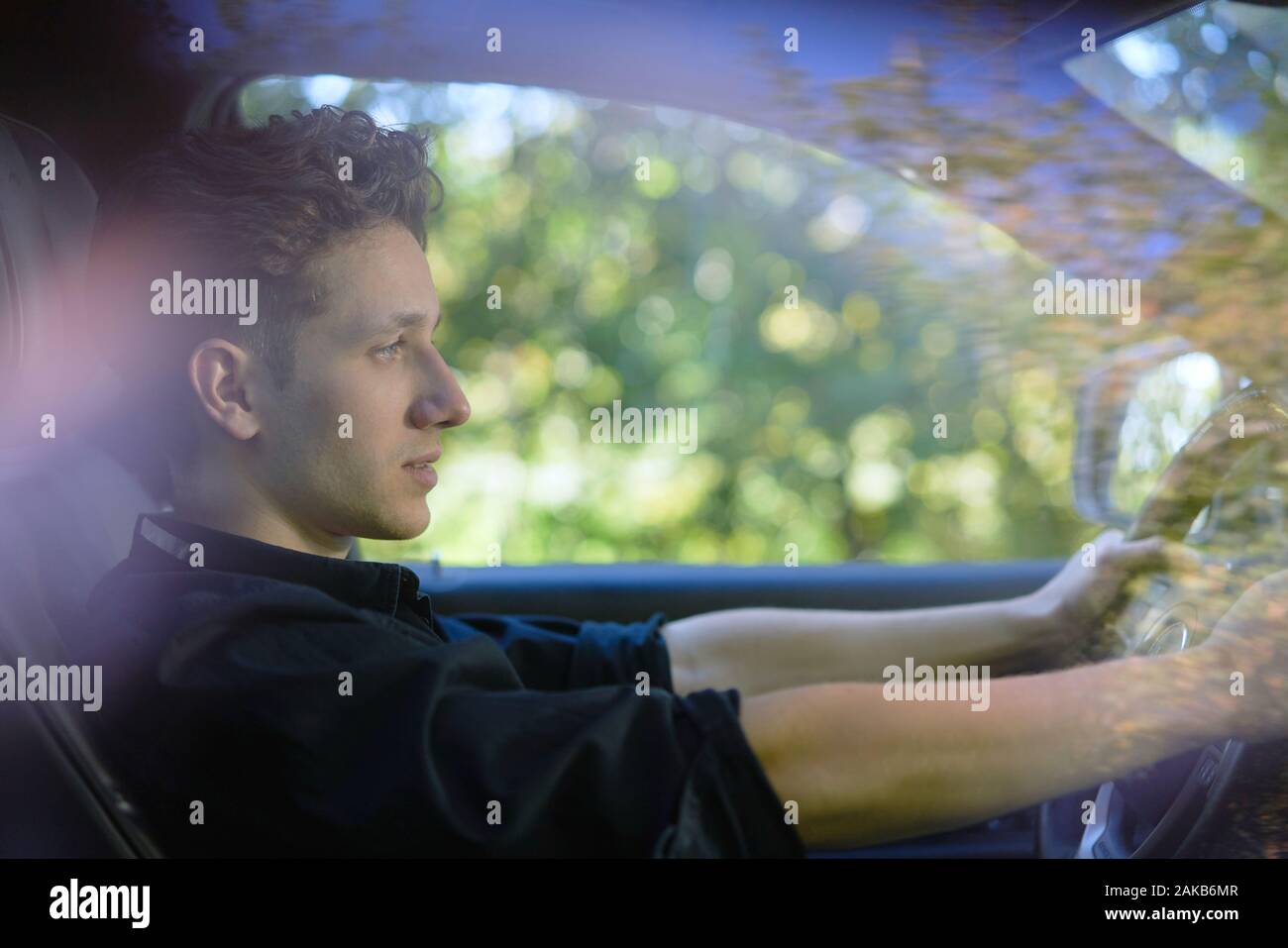 Jeune conducteur assis dans sa voiture avec les mains au volant Banque D'Images