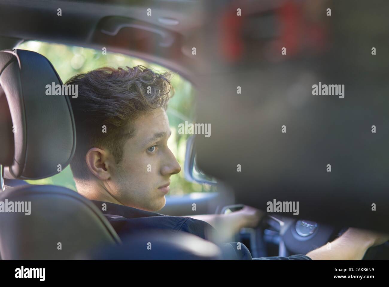 Portrait d'un jeune conducteur avec les mains sur la roue Banque D'Images