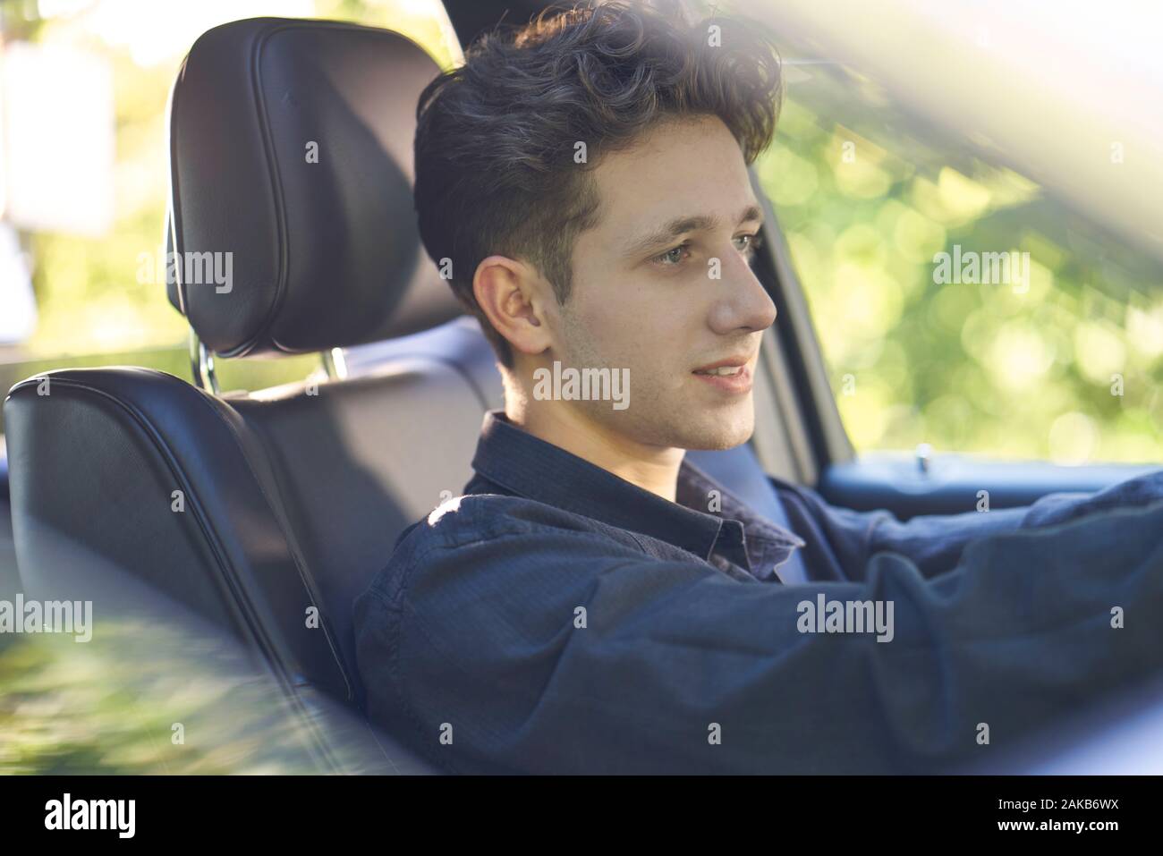 Jeune conducteur assis dans un siège noir avec un visage détendu et heureux Banque D'Images