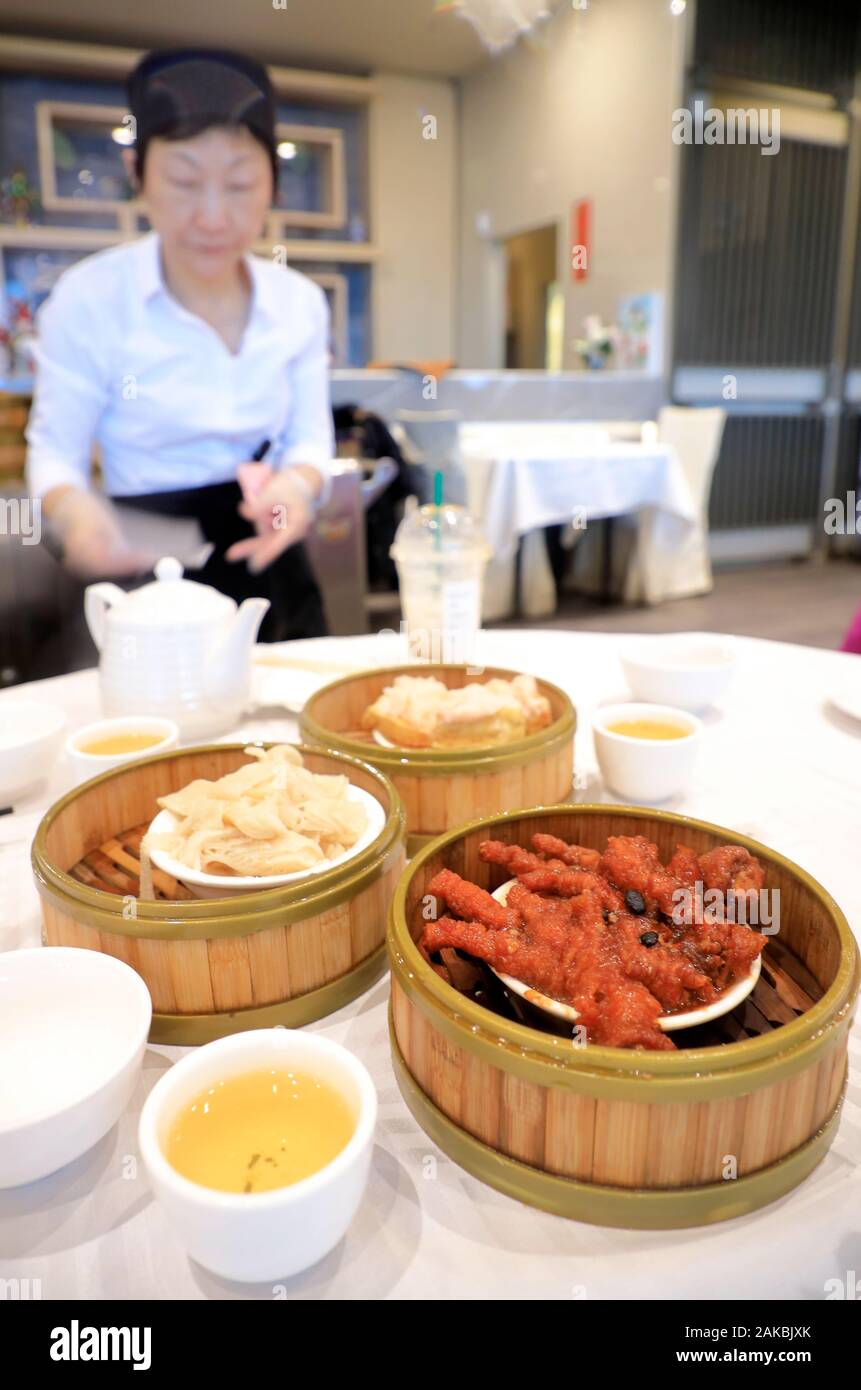 Poulet à la vapeur pieds avec sauce aux haricots noirs un célèbre plat de dim sum servis avec du thé dans un restaurant Imperial, spécialiste des dim sum dans le quartier chinois avec une serveuse dans l'arrière-plan.montreal.quebec.Canada Banque D'Images