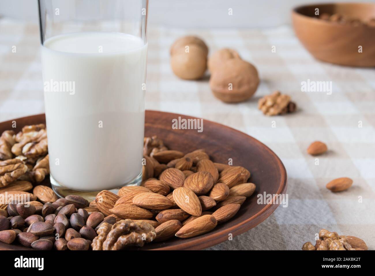 Concept de saine alimentation, amandes, noix de pin, les noix et un verre de lait dans une assiette sur la table Banque D'Images