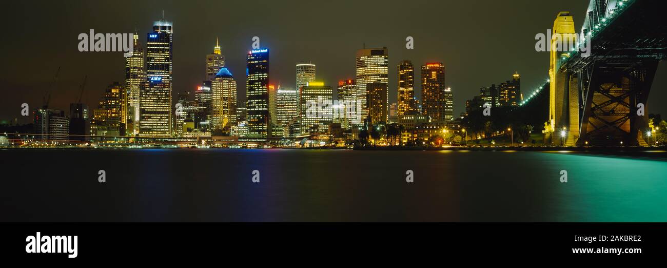 Au bord de l'eau bâtiments éclairés la nuit, Sydney Harbour Bridge, Sydney, New South Wales, Australia Banque D'Images