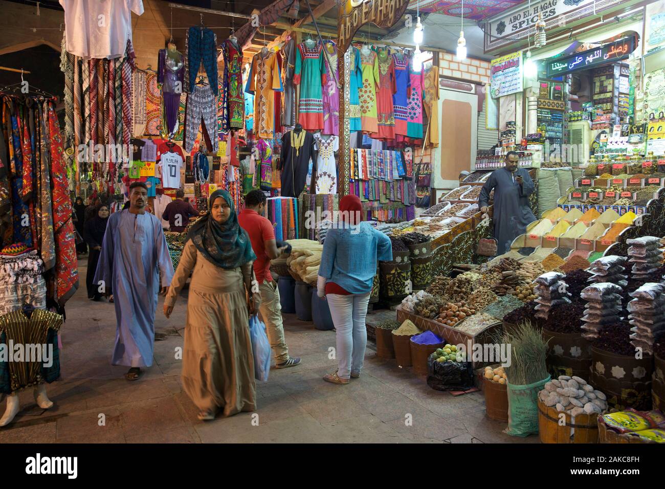 L'Égypte, de la Haute Égypte, Assouan, Les Égyptiens l'errance entre les peuplements d'épices et de vêtements colorés dans une allée couverte du souk Banque D'Images