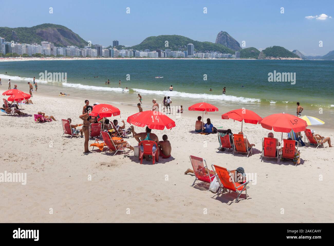 Brésil, état de Rio de Janeiro, ville de Rio de Janeiro, la plage de Copacabana, Carioca paysages entre mer et montagne classés au Patrimoine Mondial de l'UNESCO, transats et parasols rouge sièges Banque D'Images