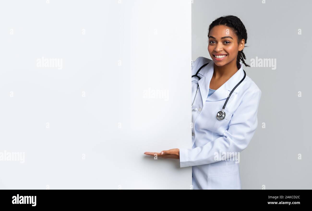 Femme médecin musulman noir blanc pointant sur des annonces avec part, présenter quelque chose, l'espace libre pour votre texte Banque D'Images