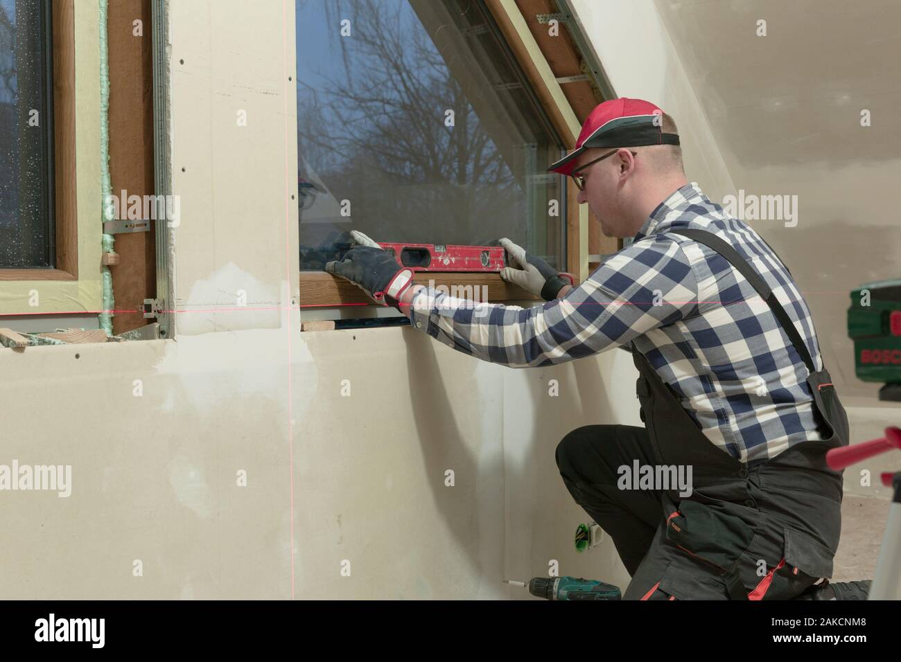 Homme à homme, la construction de l'installation dans une nouvelle fenêtre PVC isolé et rempli un mur sec grenier. Banque D'Images