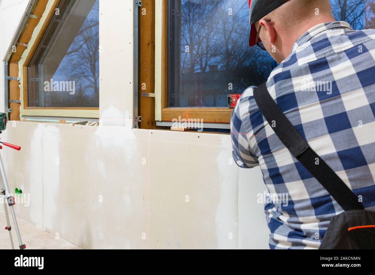 Homme à homme, la construction de l'installation dans une nouvelle fenêtre PVC isolé et rempli un mur sec grenier. Banque D'Images