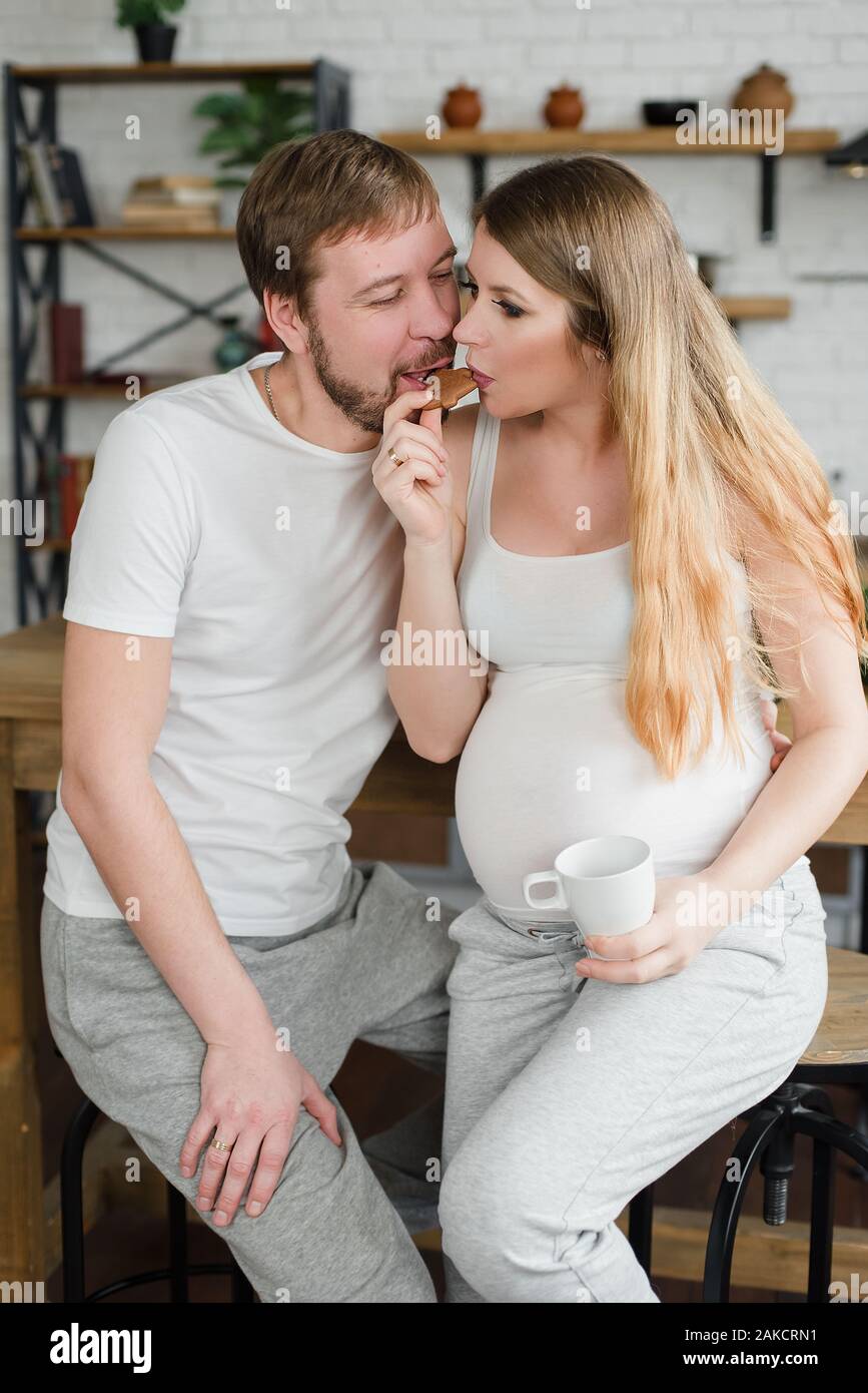 Femme enceinte et Mari le petitdéjeuner à la cuisine boire du café ou du jus de fruit et s
