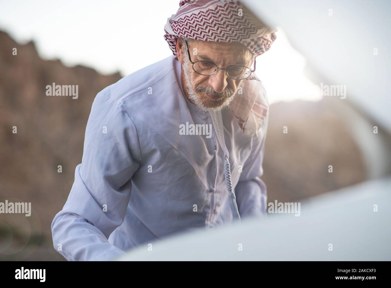 Fixation de l'homme arabes Senior sa voiture à l'extérieur Banque D'Images