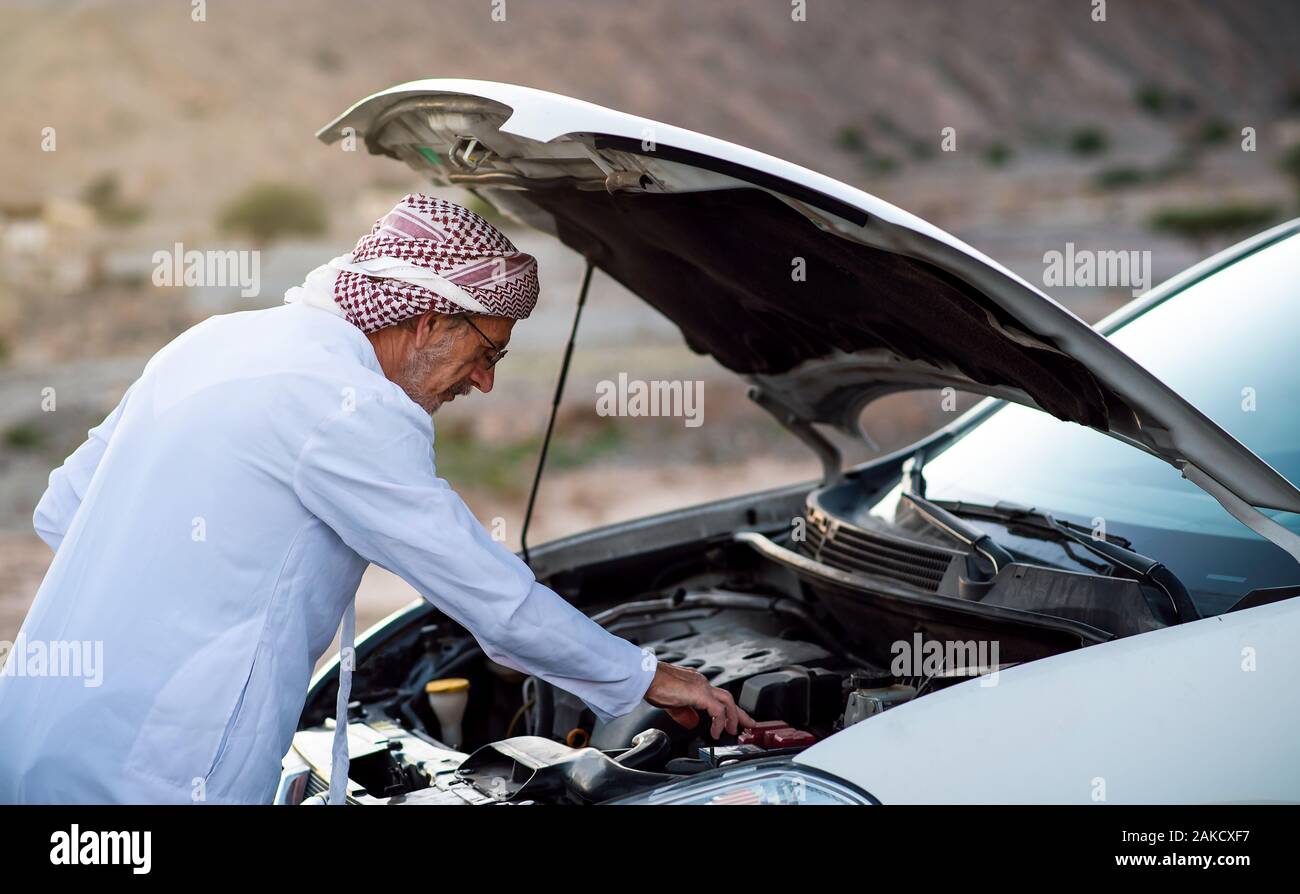 Fixation de l'homme arabes Senior sa voiture à l'extérieur Banque D'Images