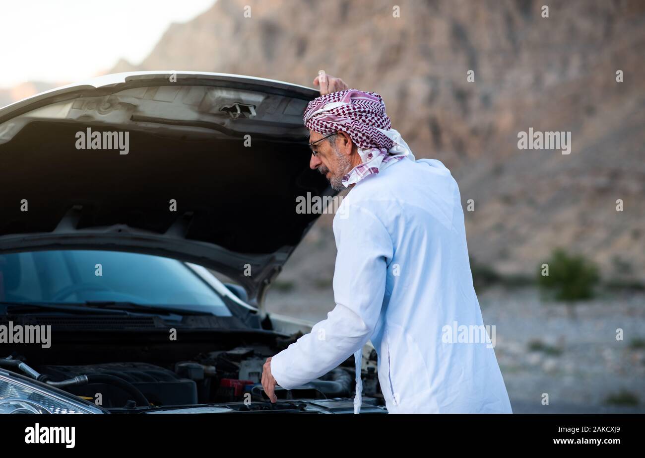 Fixation de l'homme arabes Senior sa voiture à l'extérieur Banque D'Images