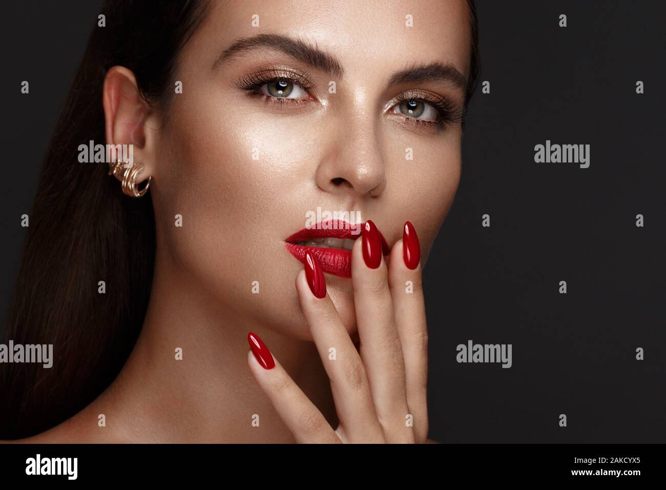Belle fille avec un classique le maquillage et les ongles rouges. Conception de manucure. Beauté Visage. Banque D'Images