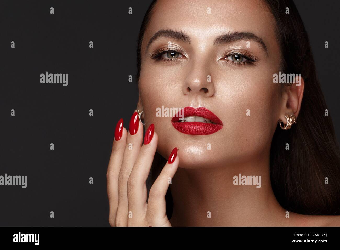 Belle fille avec un classique le maquillage et les ongles rouges. Conception de manucure. Beauté Visage. Banque D'Images