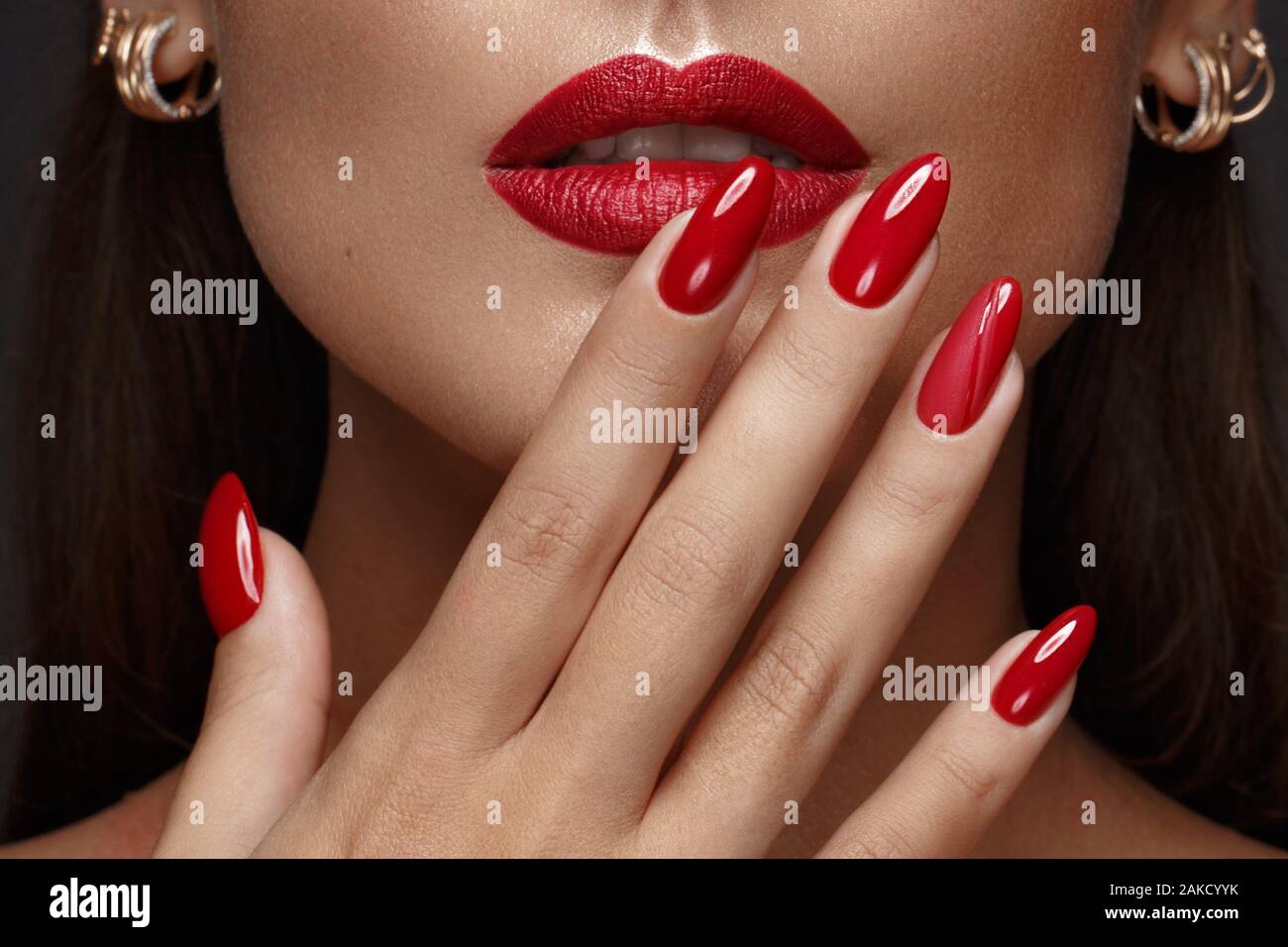 Belle fille avec un classique le maquillage et les ongles rouges. Conception de manucure. Beauté Visage. Banque D'Images