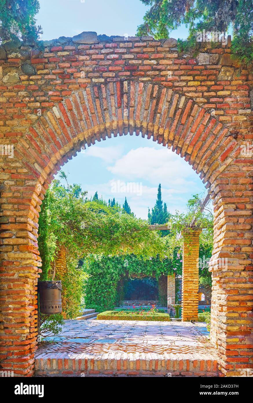 La vue sur le jardin luxuriant Alcazaba médiévale par l'arc en fer à cheval, Malaga, Espagne Banque D'Images