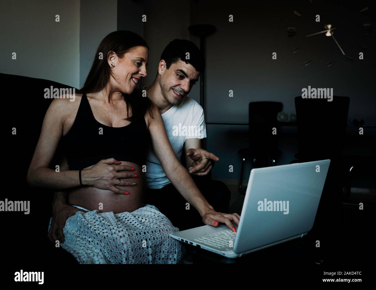 Portrait of a happy young pregnant woman shopping online tout en étant assis sur un canapé et un ordinateur portable Banque D'Images