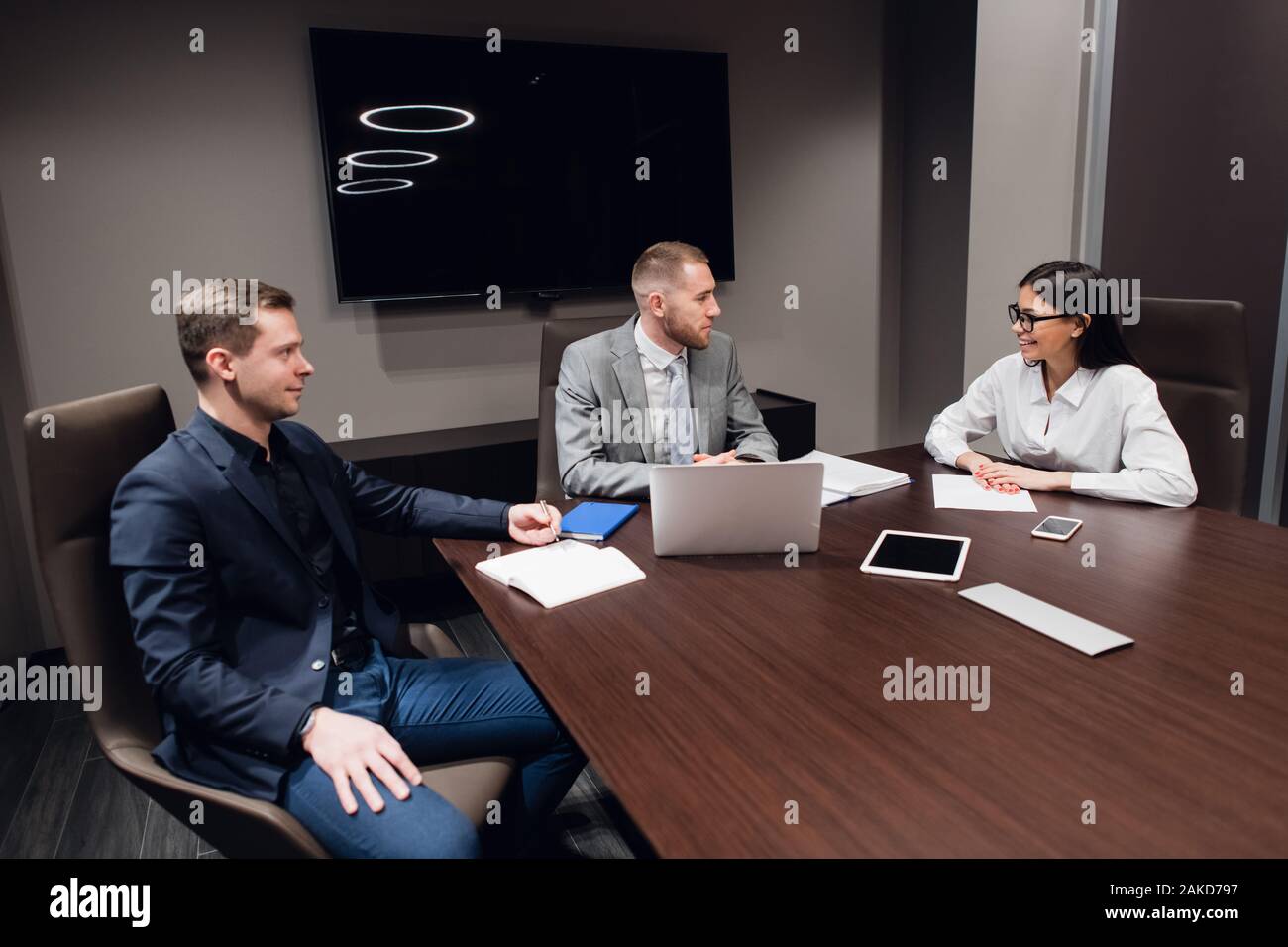 Jeune entreprise, l'entreprise créative des gens de différentes races et de l'âge se rassembler dans une salle de réunion dans l'intérieur de bureau moderne sombre, vivously à discuter. Banque D'Images